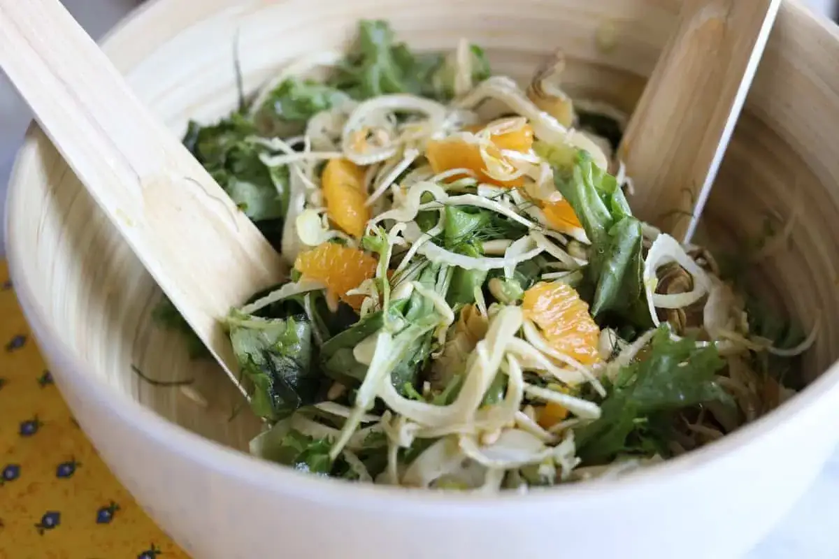 Salade fra&icirc;che avec des morceaux d'orange, du fenouil et une vinaigrette l&eacute;g&egrave;re. Les ustensiles en bois sont pr&ecirc;ts &agrave; servir.
