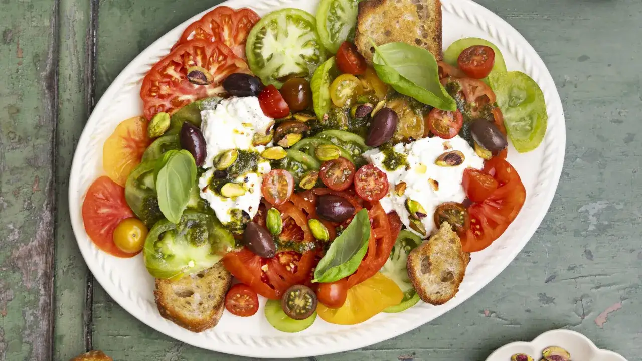 Salade color&eacute;e de tomates anciennes, burrata cr&eacute;meuse, olives, pistaches et cro&ucirc;tons. Une recette burrata froide parfaite pour l'&eacute;t&eacute;.
