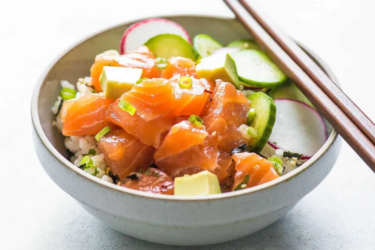 Un d&eacute;licieux poke bowl sant&eacute; avec du saumon frais, de l'avocat, du concombre et des radis sur un lit de riz.
