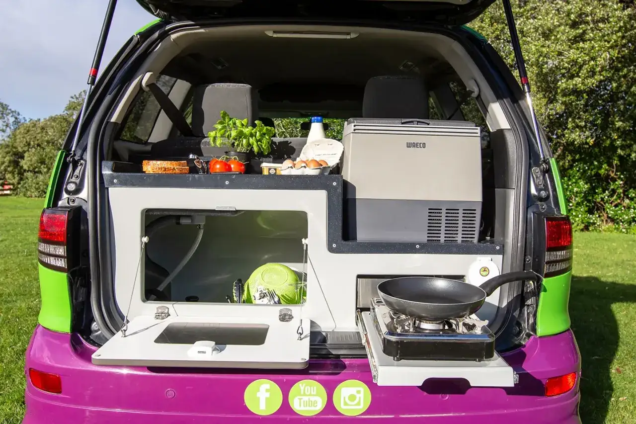 Aménagement de van pour manger dans sa voiture le midi : cuisine, frigo, évier et réchaud. Idéal pour un pique-nique improvisé.