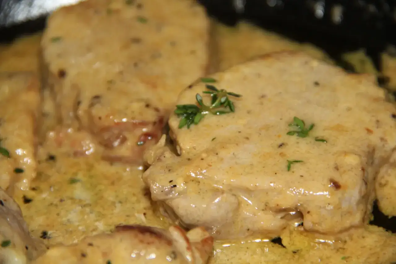 Délicieux morceaux de viande de porc nappés d'une onctueuse sauce moutarde, parsemés de quelques herbes fraîches. Un plat savoureux.