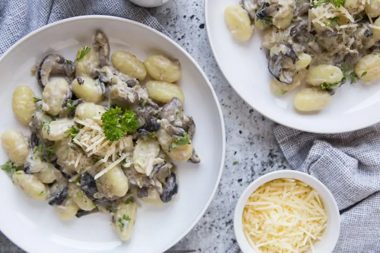 Gnocchi crémeux aux champignons, parsemés de persil frais et de parmesan râpé. Un plat réconfortant et savoureux.