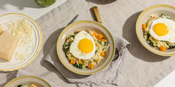 Risotto crémeux aux courges et épinards, garni d'un œuf au plat. Une recette avec des œufs qui promet un repas réconfortant.