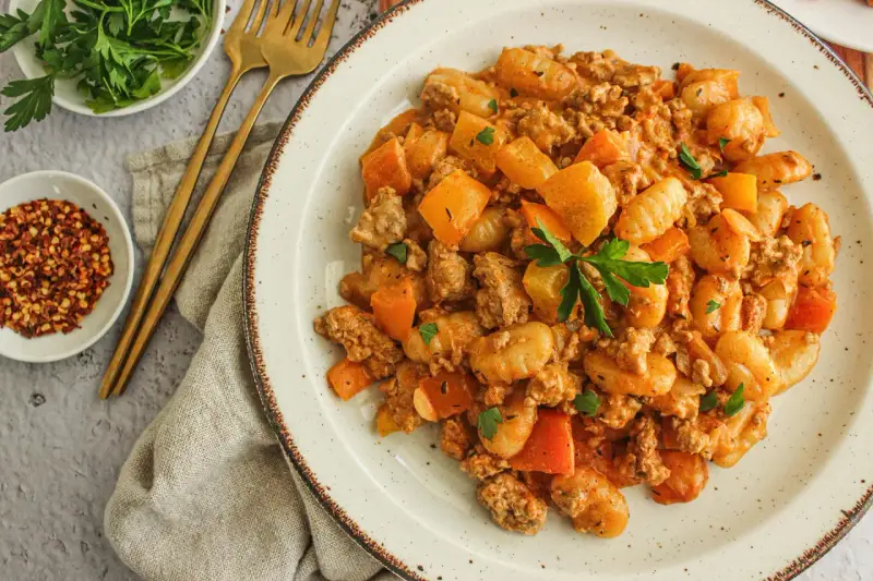 Délicieux sauté boeuf haché asiatique avec des gnocchis et des morceaux de carottes, garni de persil frais.