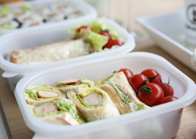 Sandwichs et tomates cerises dans une boîte, une idée de recette lunch box facile et rapide pour un repas sain.