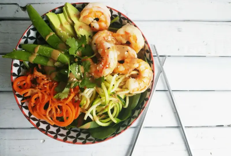 Un poke bowl crevette facile et coloré avec avocat, carottes spirales, courgettes en nouilles et pois gourmands.